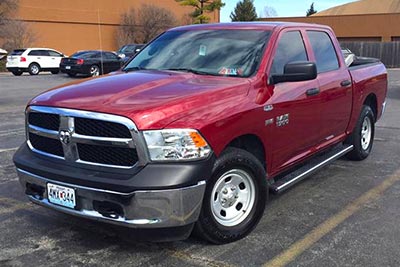 A red Dodge Ram 1500 with the exhaust drone eliminating and deep sounding Paradox Performance Muffler. The pickup truck is parked in a lot, photographed from the front three-quarter angle.